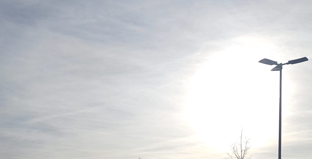 Am Abend nicht abschalten.Sonne hinter feinen Wolken neben einer Straßenlaterne – ruhiger Abendhimmel